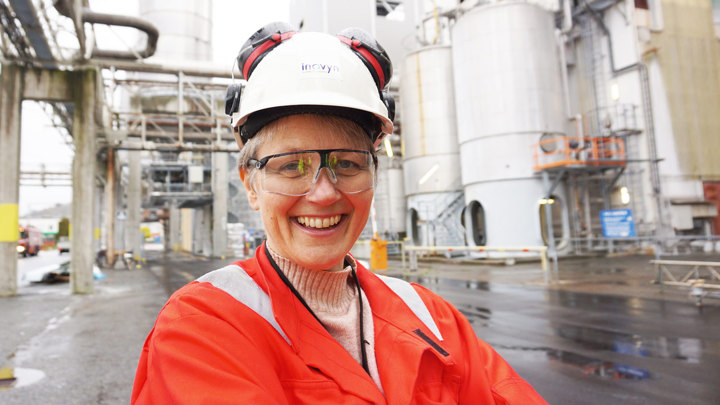 portrett av kvinne, rød arbeidsjakke, hjelm, vernebriller