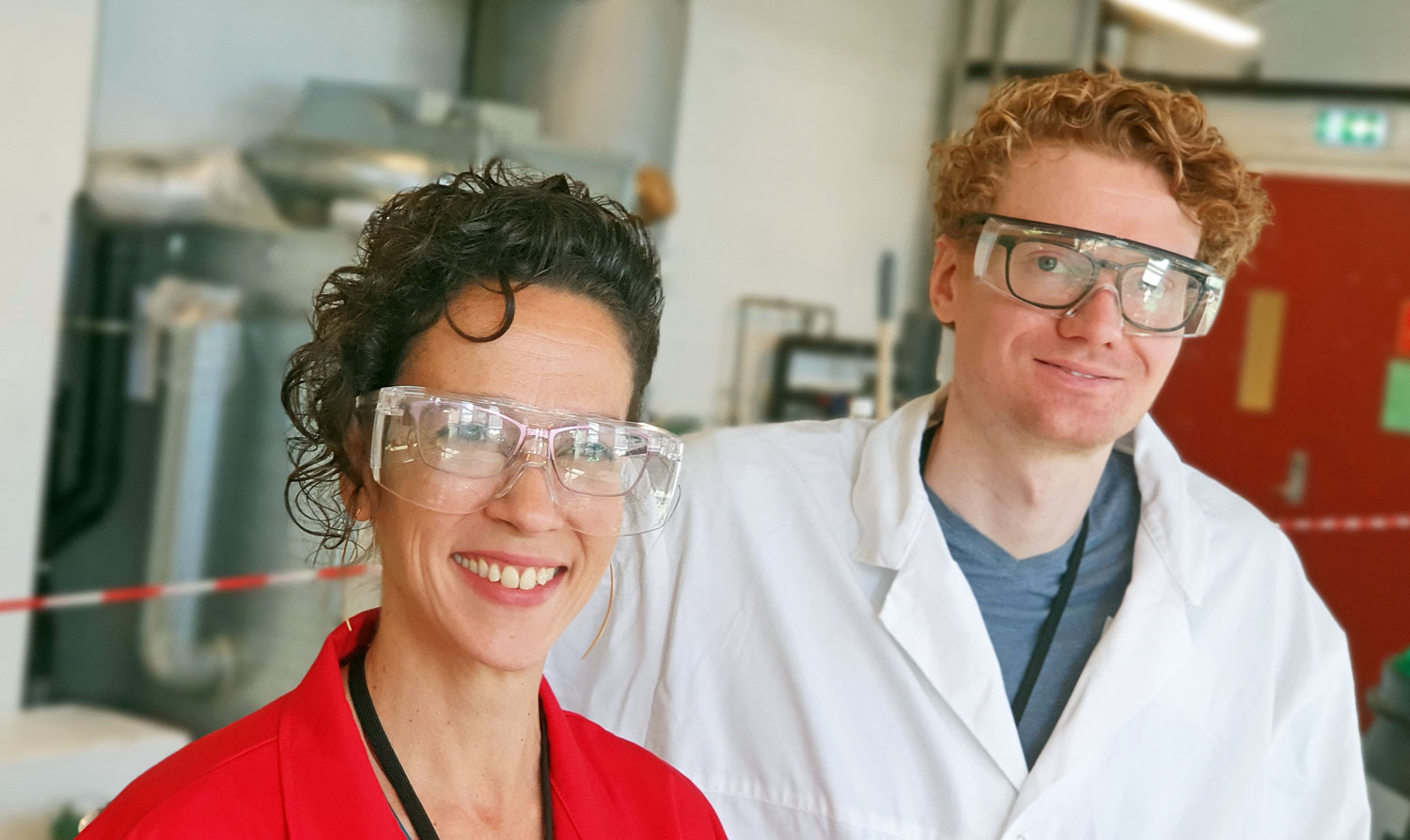 portrett av to forskere, kvinne med rød jakke og mann i hvit lab-frakk