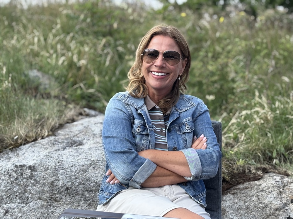 woman sitting in chair, sunglasses, arms folded, green grass,