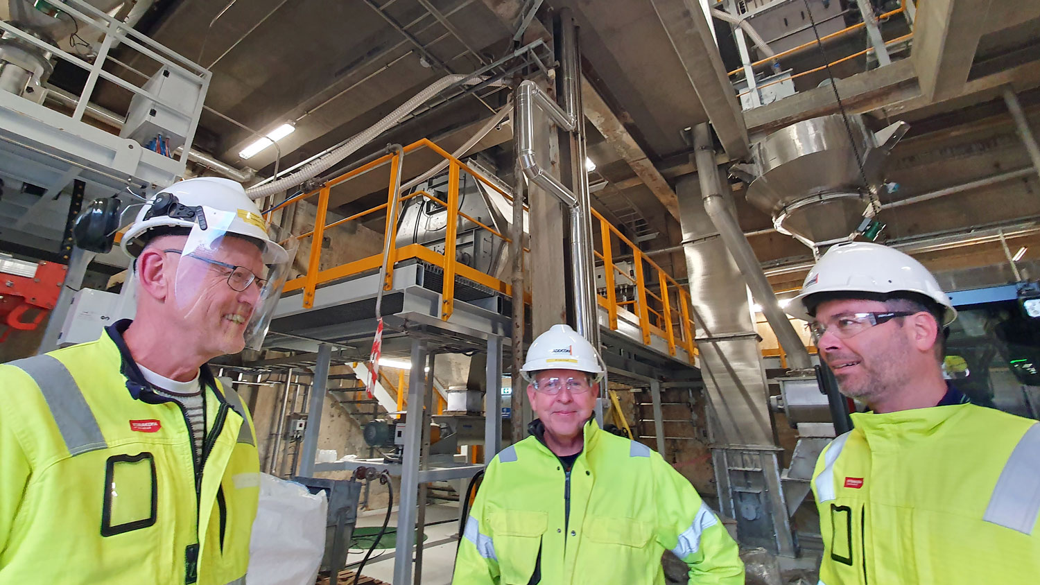 three men, yellow working clothes, process industry