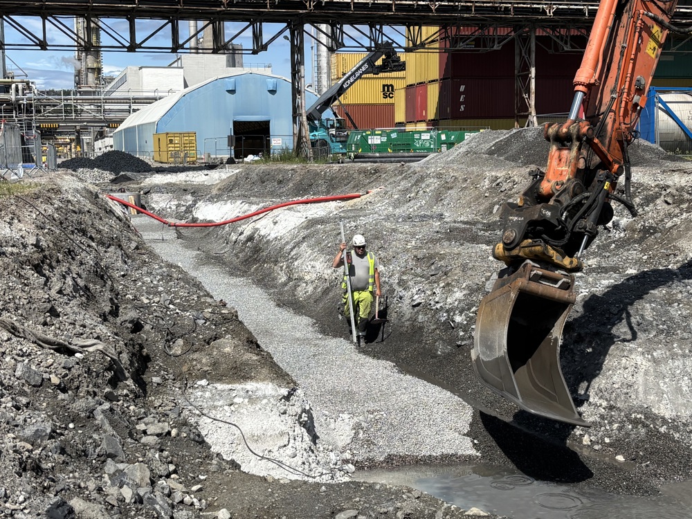 wide ditch, excavator, man standing in the ditch, construction area.