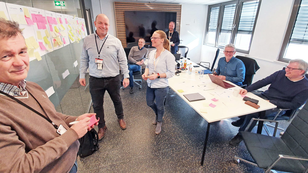 people standing and sitting in meeting room, creative session, post-its on the wall