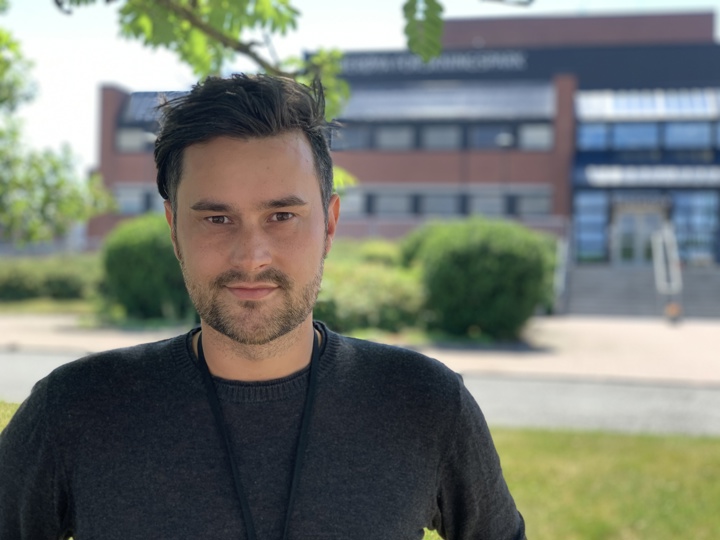 portrett av ung mann foran rød mursteinsbygning, stort inngangsparti og trapper