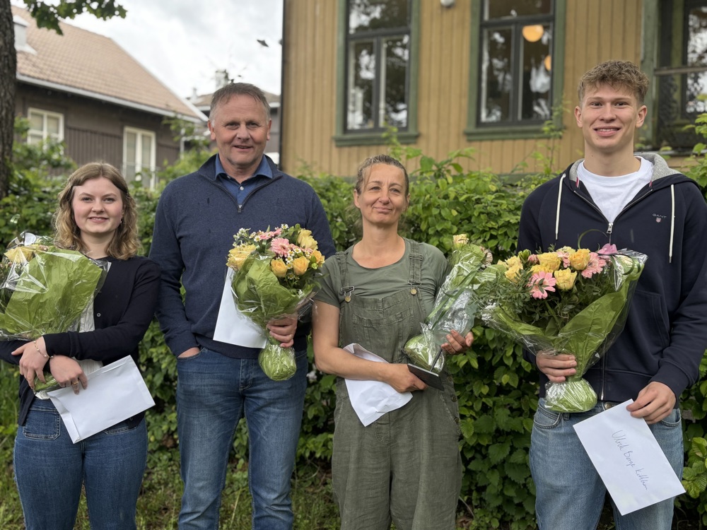 fire personer står på rekke, hver med blomsterbukett, gult hus, hage