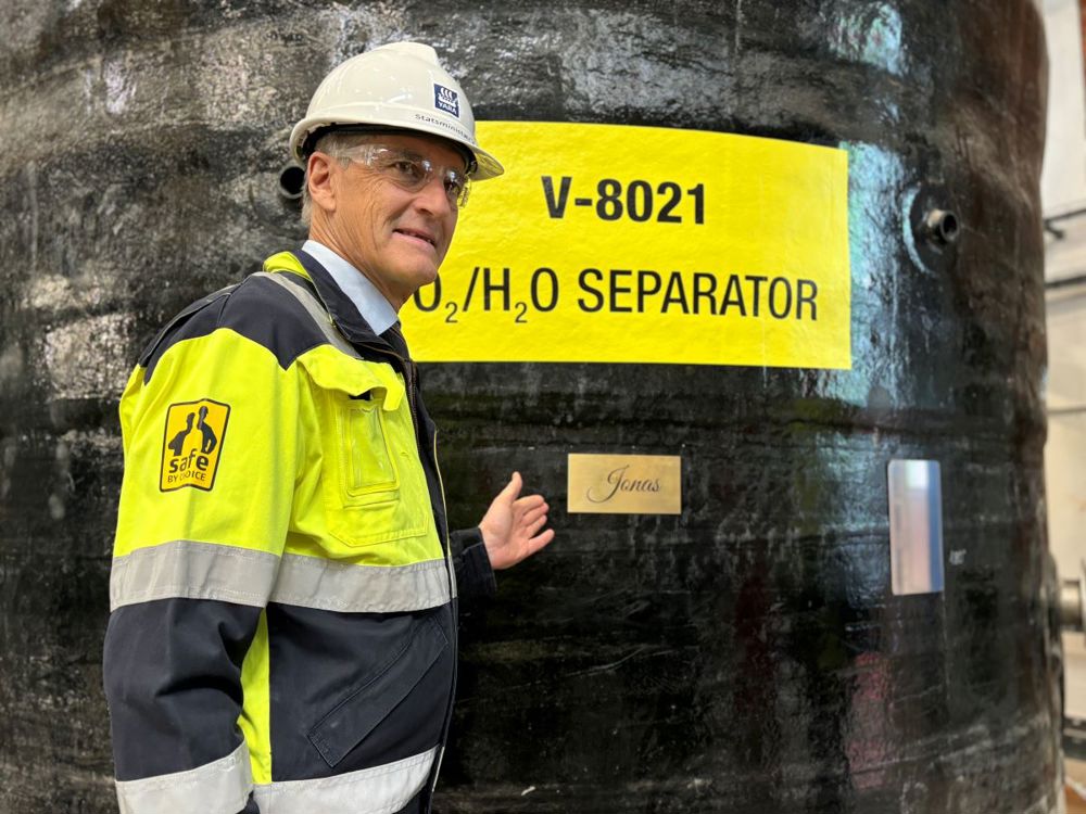 statsminister står ved siden av tank med navnet han på.