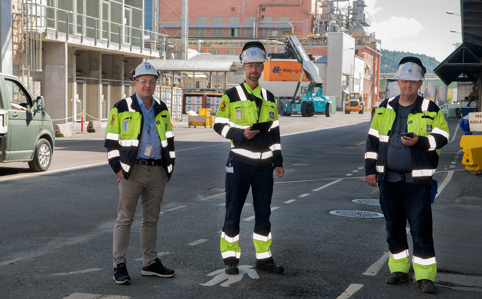 tre menn står ute i gate i industripark med måleverktøy for 5G i hendene