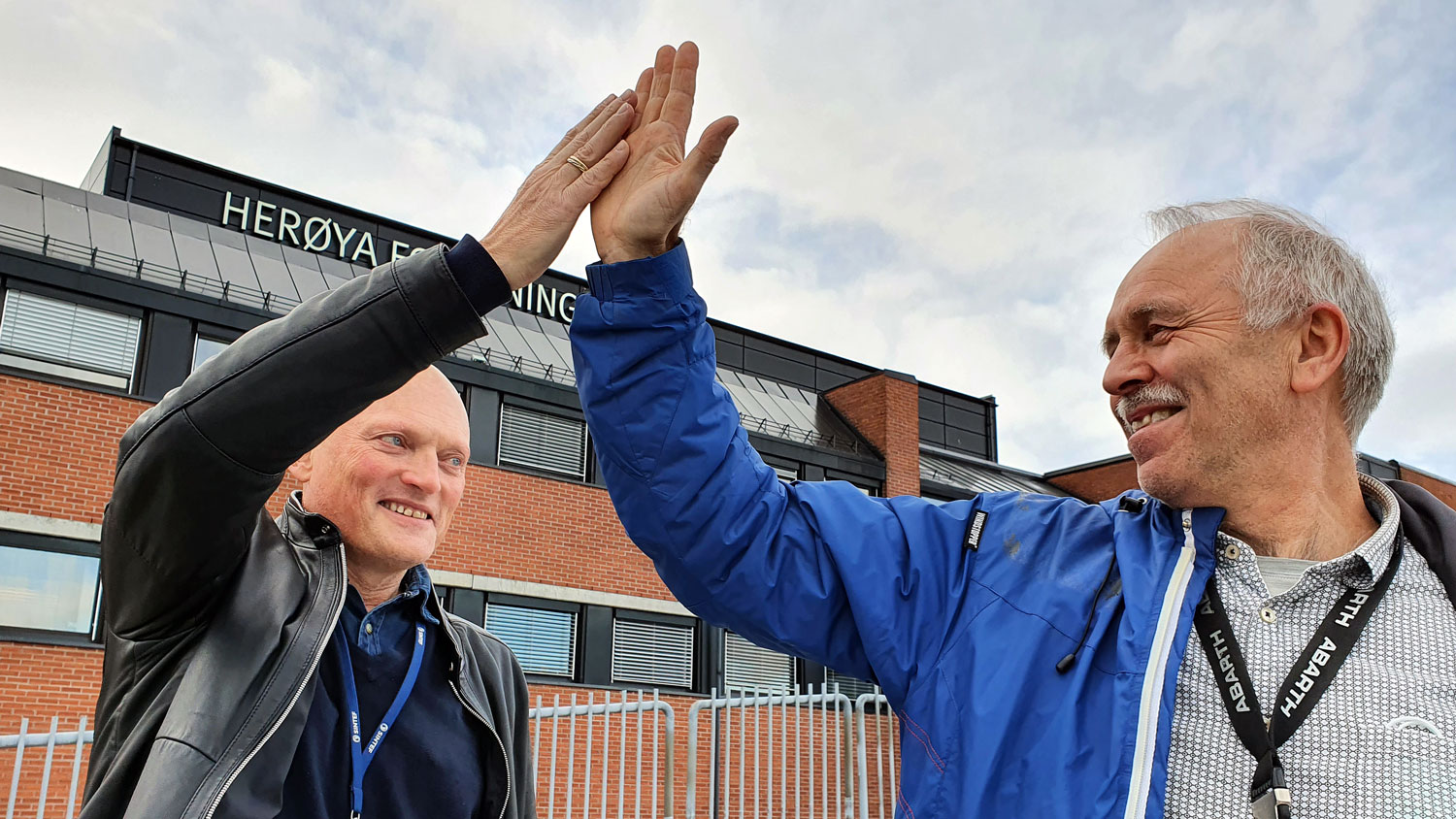 to menn, high five, hender i været, foran bygg