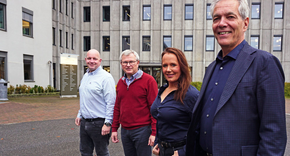 four people standing in line in front of office building