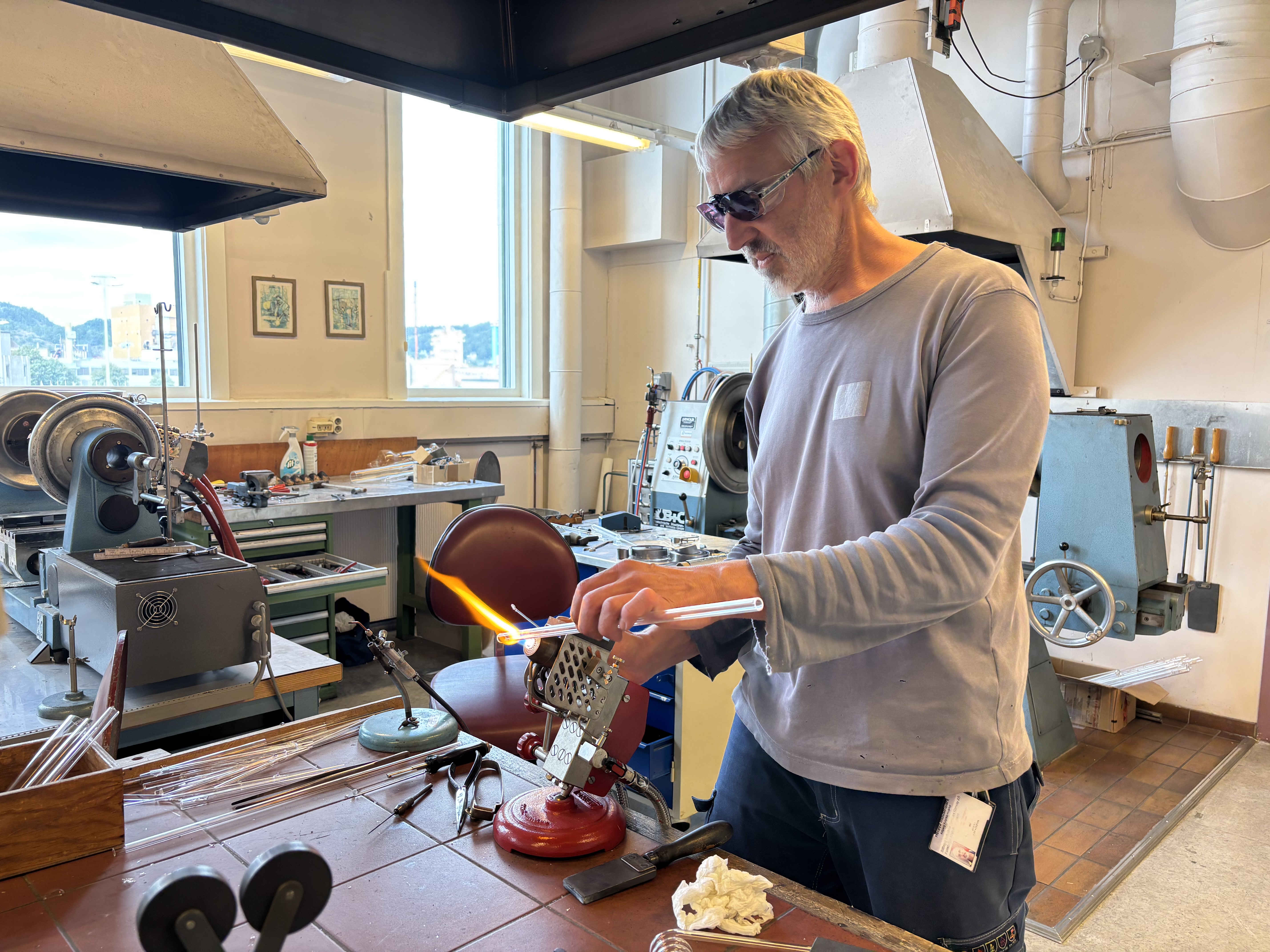glassblåser i arbeid foran flamme i verksted