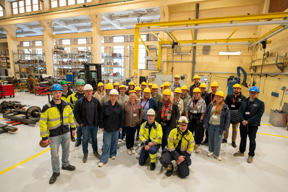 stor gruppe med gule hjelmer i et verkstedlokale