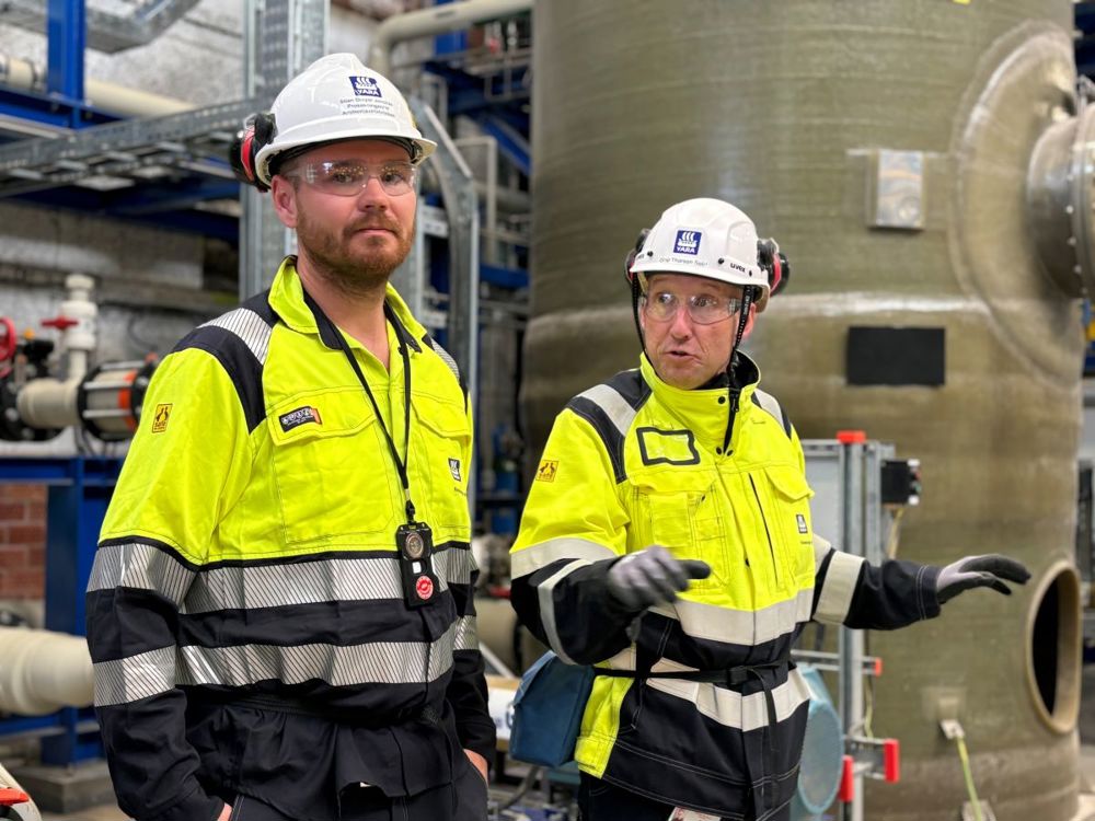 to personer, poserer, en gestikulerer og snakker til besøkende.