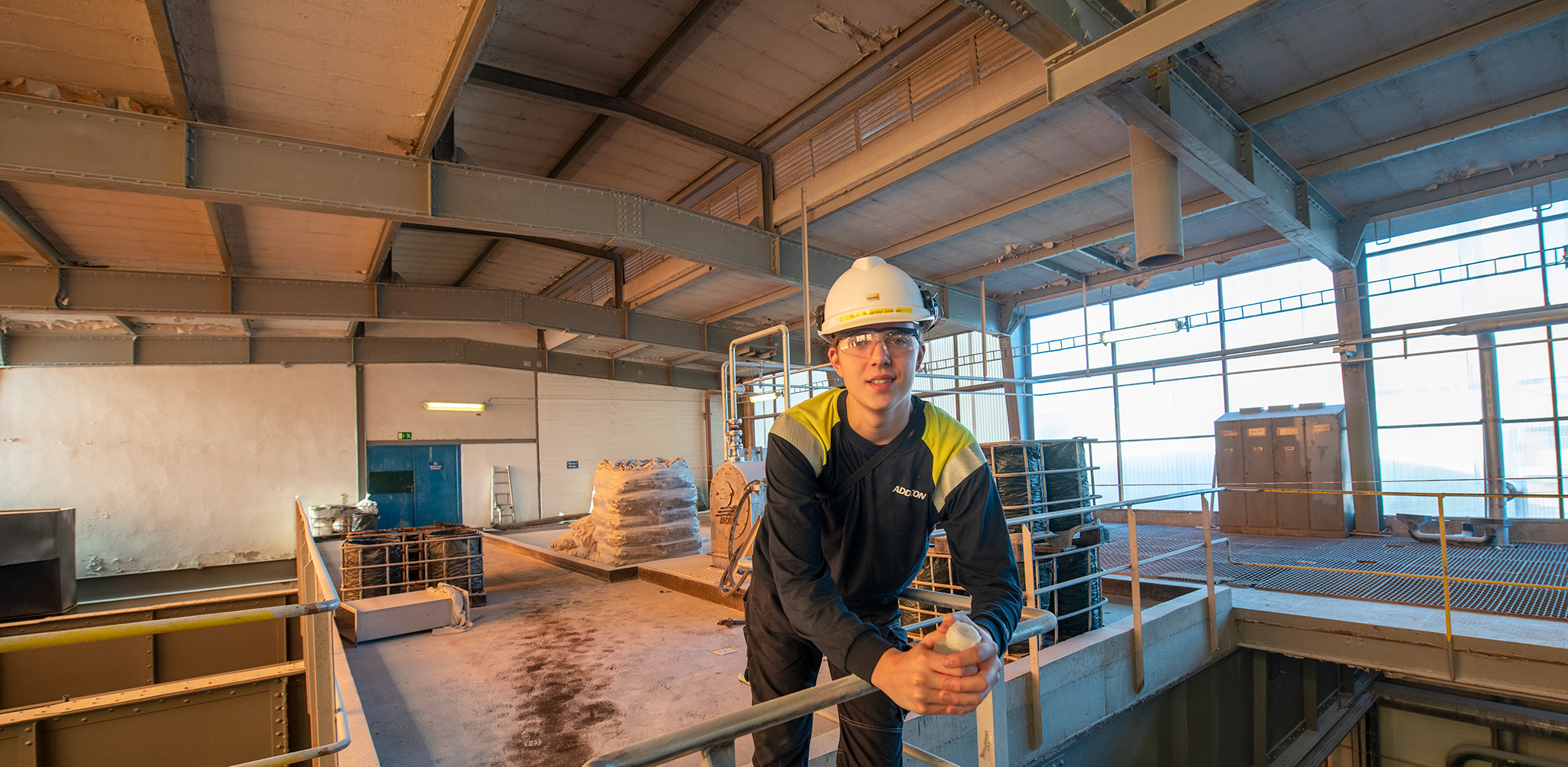 apprentice, posing, standing by a rail in a production unit