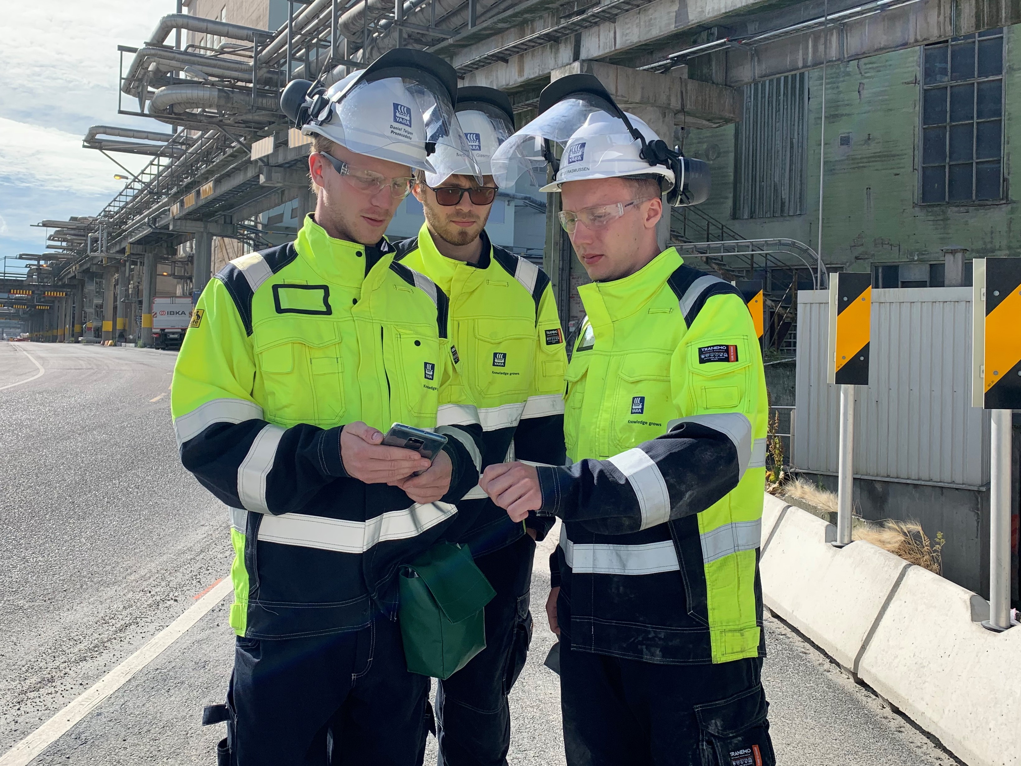 three male students standing together monitoring device showing 5G coverage