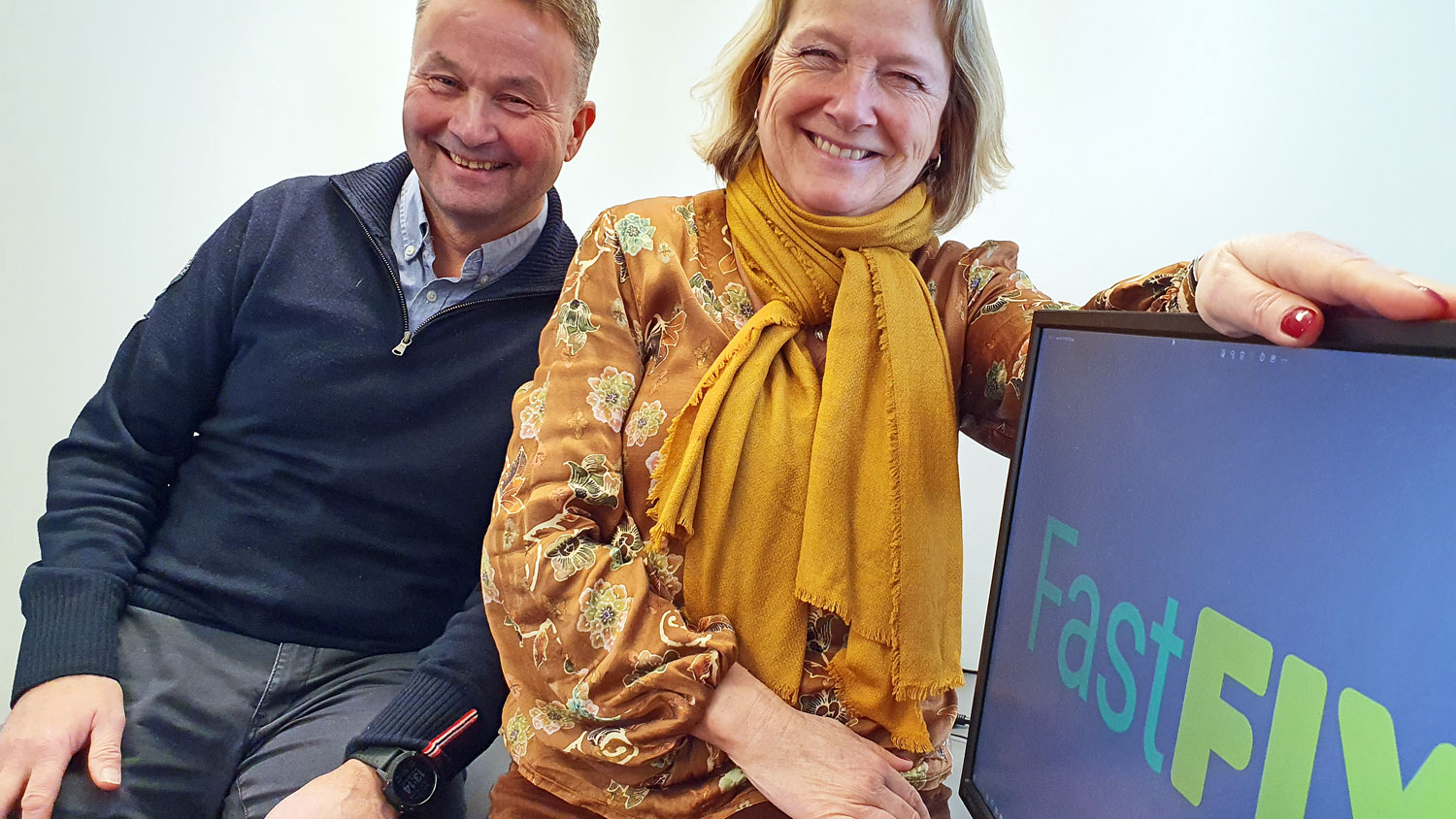 man and woman sitting by a monitor, business logo