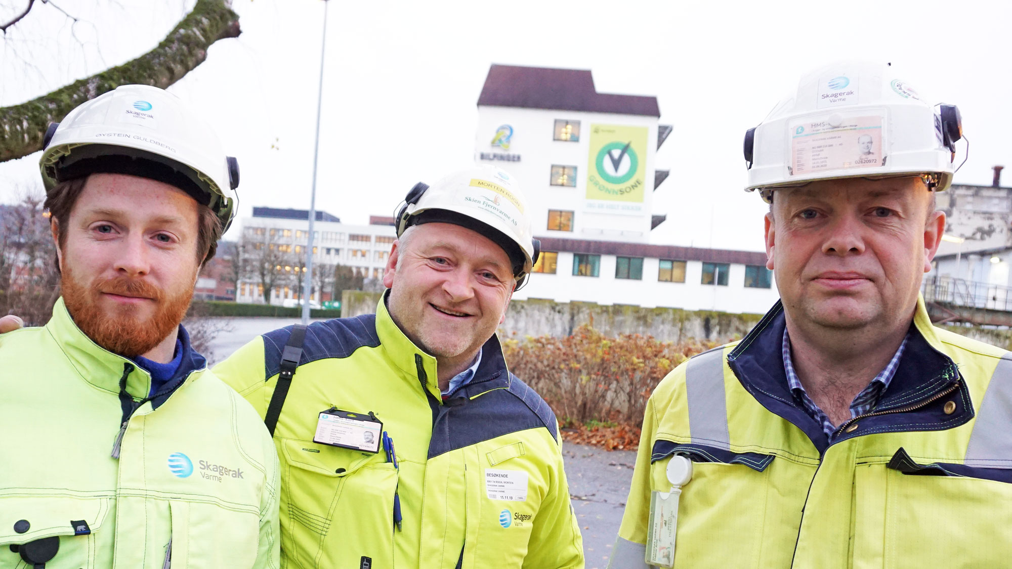 tre personer, poserer, portrett, industribygg i bakgrunnen