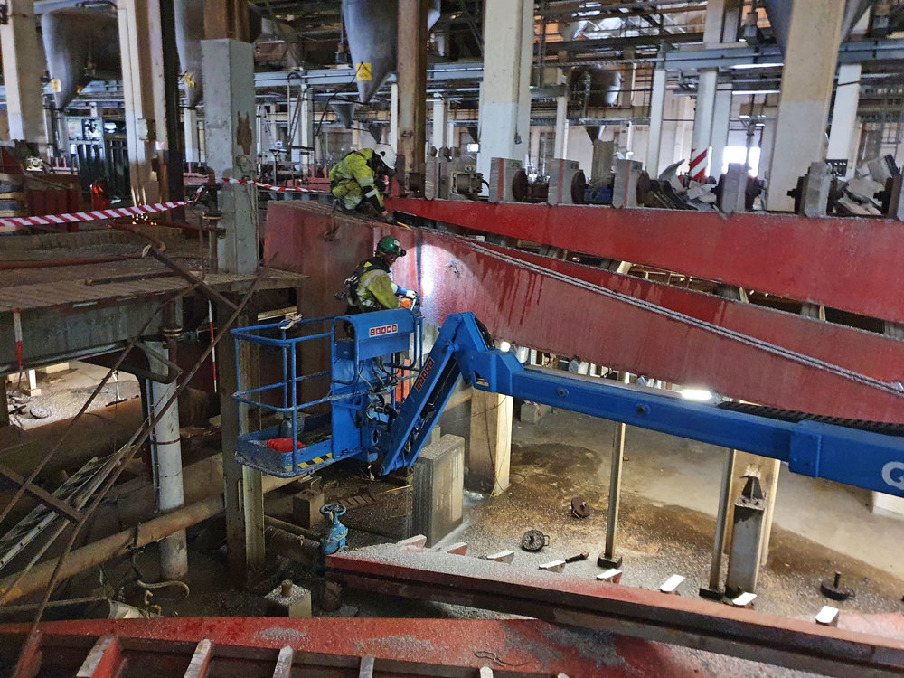 man standing in lift basket in a big old production hall