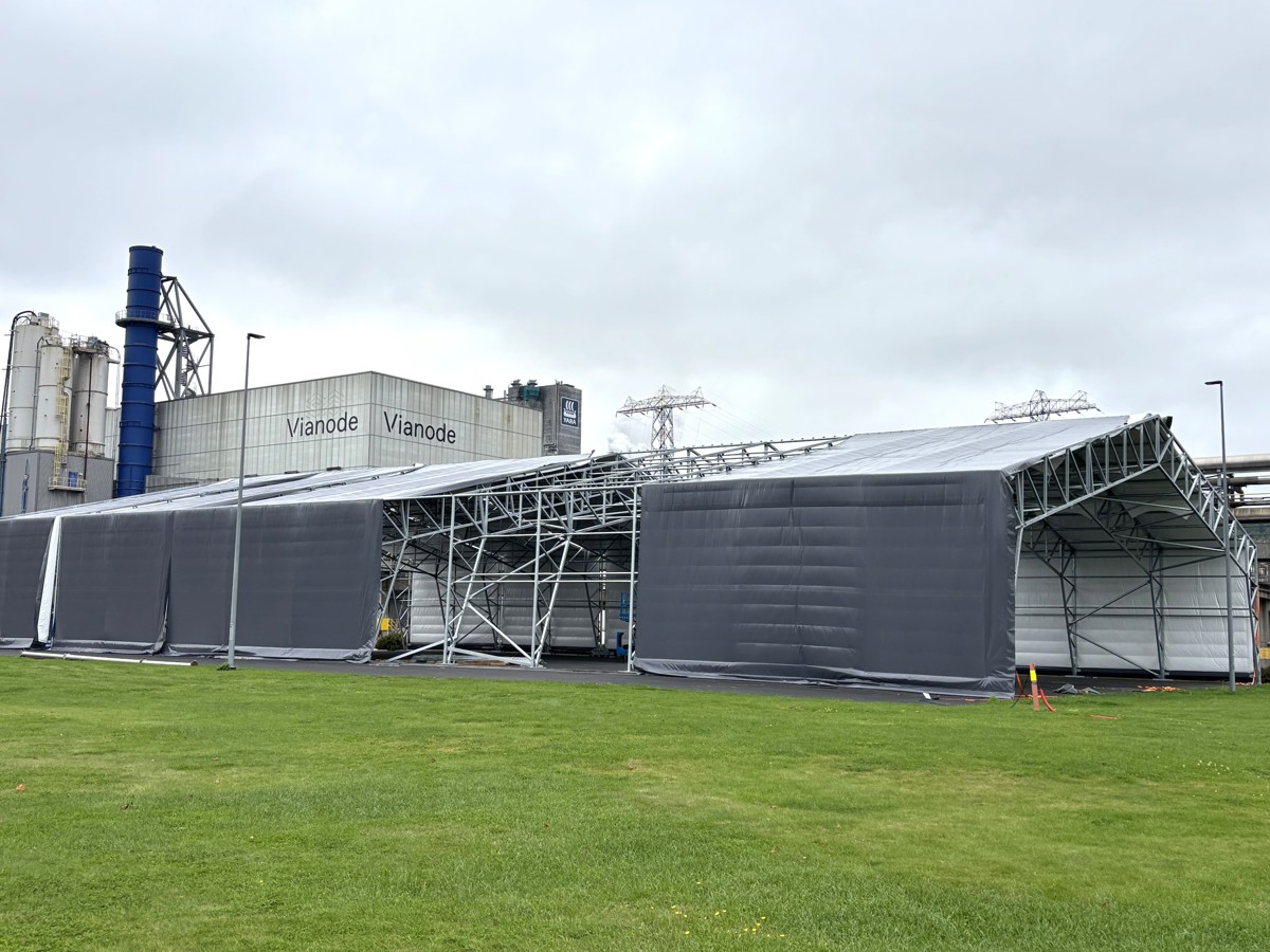 big plastic tent, industry, almost finished, green grass in front, industry buildings background.