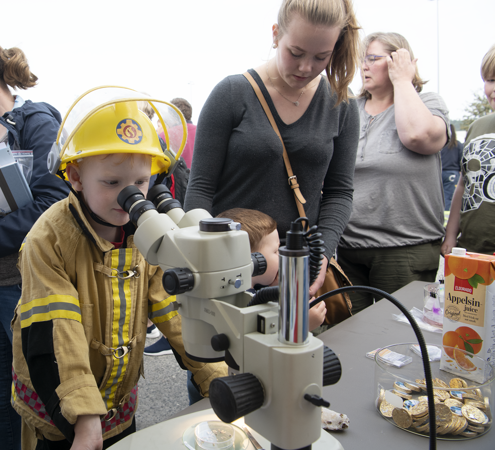 et barn kledd i brannmannuniform ser i mikroskop