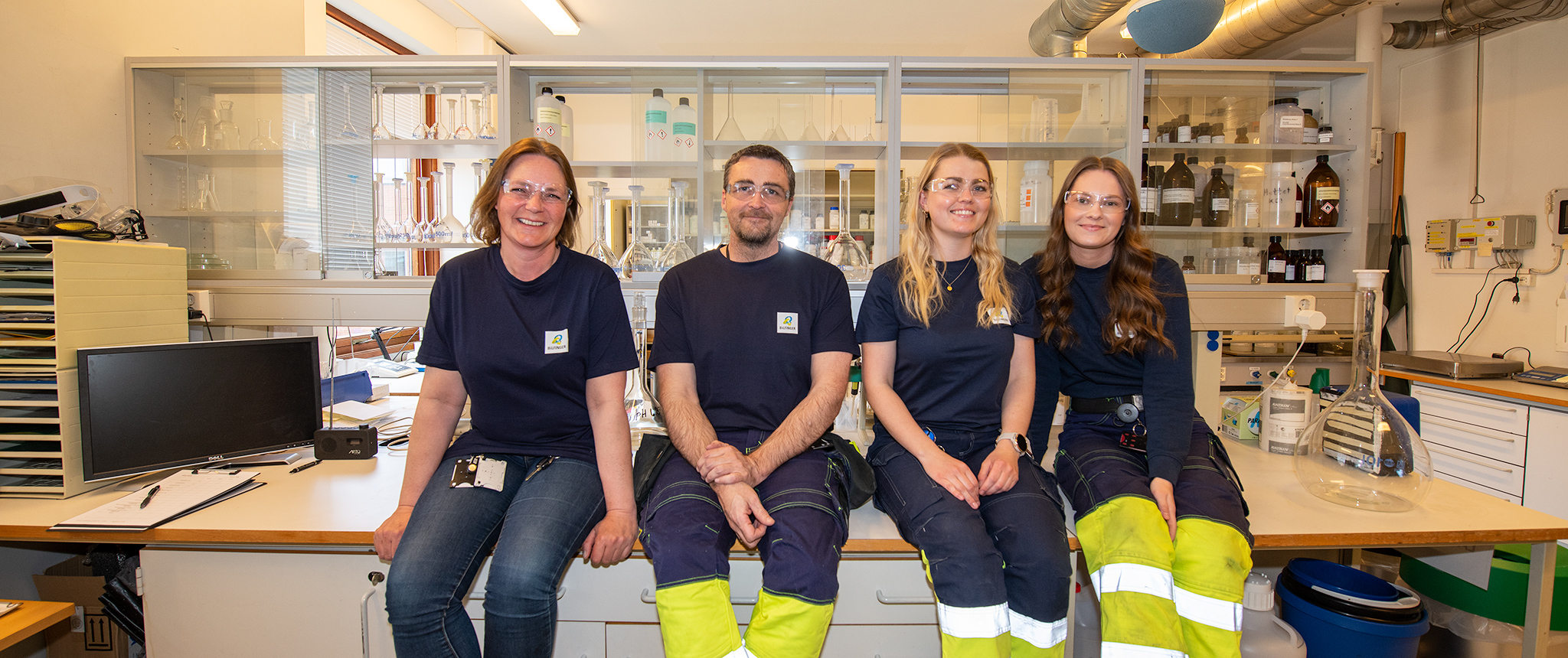 fire personer sitter på et bord i et laboratorium