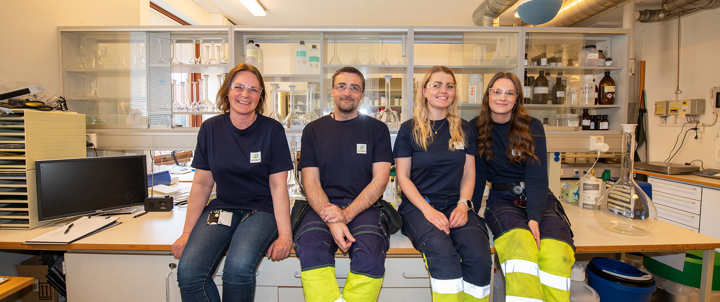 fire personer sitter på et bord i et laboratorium