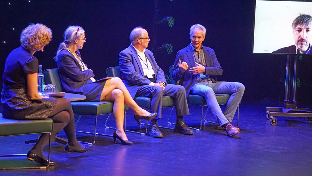 four people sitting on stage debating