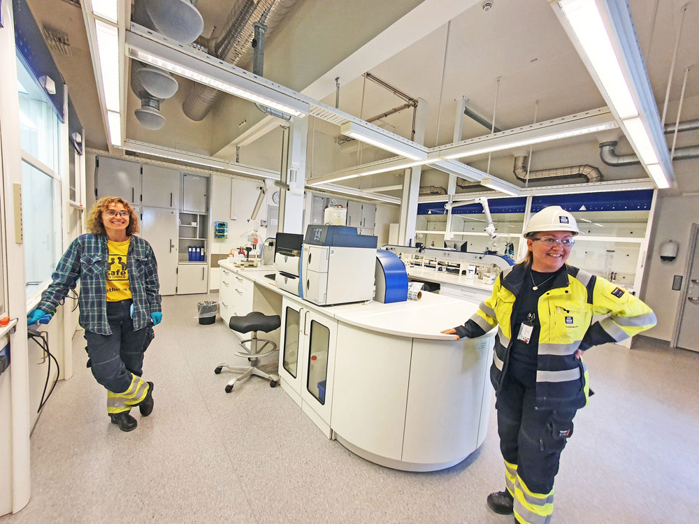 to kvinner i arbeidsklær inne på et hvitt laboratorium