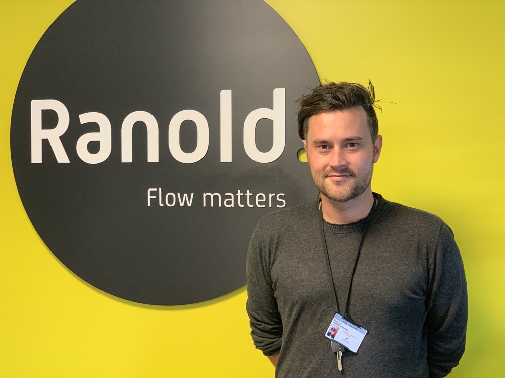 man posing, standing next to business logo on wall, office