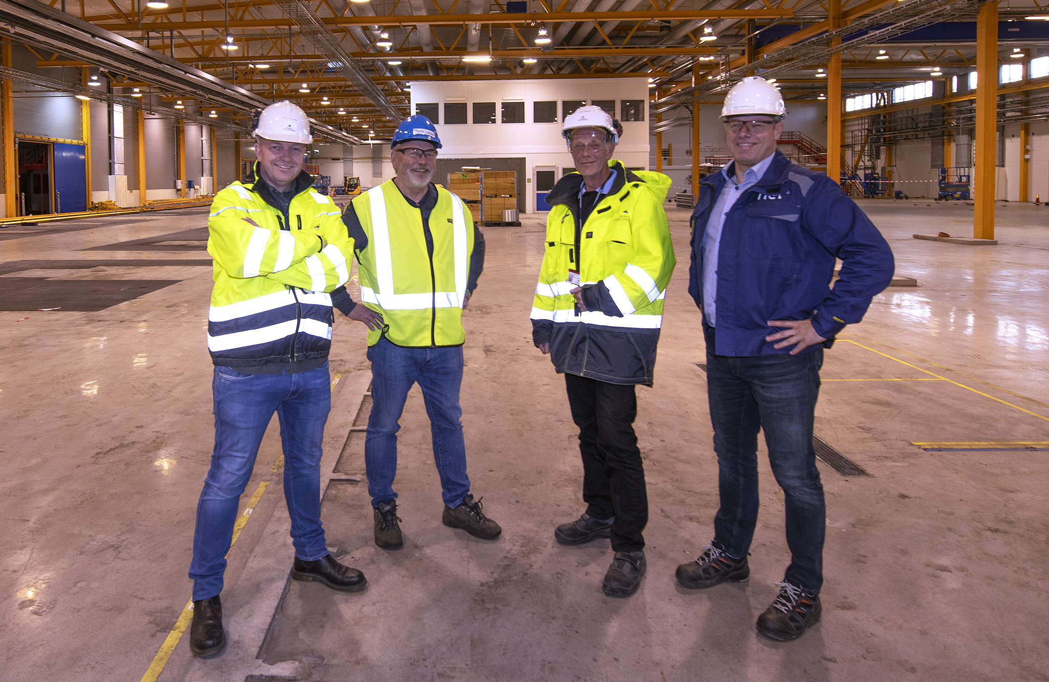 four men, posing, empty production hall