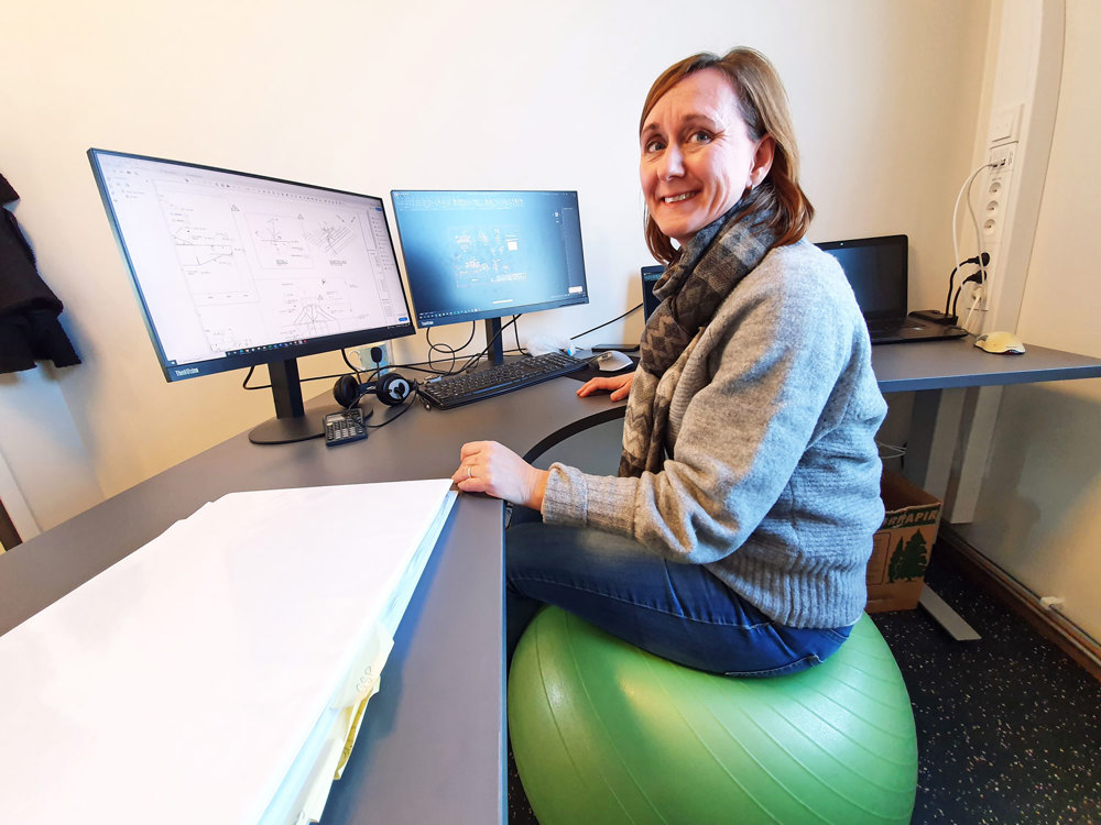 kvinne sitter på ergonomisk ball ved skrivebordet på kontoret